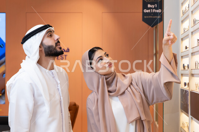 تخفيضات وخصومات وعروض، الركن الخاص بالنظارات الشمسيه الفخمه،التسوق والشراء من المولات، الاهتمام بالمظهر الخارجي والاناقه ، سيدة اماراتية تساعد الزبائن فى الاختيار ، رجل عربي خليجي اماراتي يرتدي الكندورة والغترة يقوم بقياس النظارة الشمسيه المناسبة في محل اماراتي