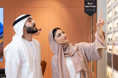 تخفيضات وخصومات وعروض، الركن الخاص بالنظارات الشمسيه الفخمه،التسوق والشراء من المولات، الاهتمام بالمظهر الخارجي والاناقه ، سيدة اماراتية تساعد الزبائن فى الاختيار ، رجل عربي خليجي اماراتي يرتدي الكندورة والغترة يقوم بقياس النظارة الشمسيه المناسبة في محل اماراتي