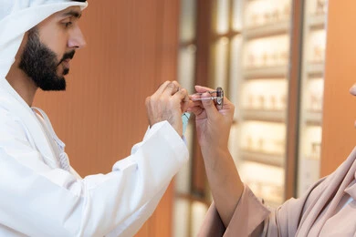 Attention to appearance and elegance, an Arab Gulf Emirati man wearing a kandura and ghutrah is trying on the suitable sunglasses in an Emirati store, discounts and promotions, the section for luxury sunglasses, shopping and buying sunglasses from the malls.