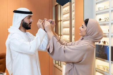 تخفيضات وخصومات وعروض ،الاهتمام بالمظهر الخارجي والاناقه ، الركن الخاص بالنظارات الشمسيه الفخمه، رجل عربي خليجي اماراتي يرتدي الكندورة والغترة يقوم بقياس النظارة الشمسيه المناسبة في محل اماراتي،  التسوق وشراء النظارات الشمسيه من المولات