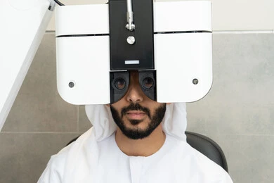 تشخيص وتحديد المشاكل البصرية، استخدام الأجهزة الحديثة المتطورة، مفهوم الخدمات والرعاية الصحية في المشافي والمراكز الطبية، التأكد من صحة البصر ، رجل عربي خليجي اماراتي يقوم بفحص عينيه بجهاز المنظار العيني، تقييم مدى الرؤية والكشف عن الامراض العينية