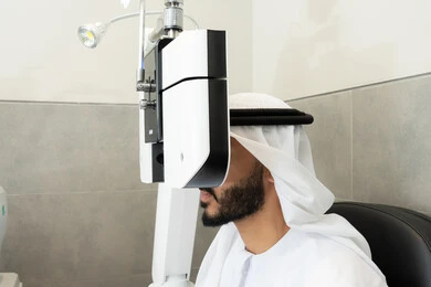 The concept of healthcare services in hospitals and medical centers, ensuring the health of vision, an Arab Gulf Emirati man examining his eyes with an ophthalmoscope, diagnosing and identifying visual problems, assessing the extent of vision and detecting eye diseases, using advanced modern devices.