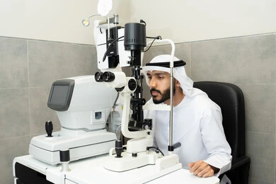 Diagnosis and identification of visual problems, the concept of services and healthcare in hospitals and medical centers, assessment of visual acuity and detection of eye diseases, use of advanced modern devices, an Arab Gulf Emirati man examining his eyes with an ophthalmoscope, ensuring the health of vision.