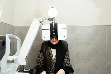 تقييم مدى الرؤية والكشف عن الامراض العينية ، مفهوم الخدمات والرعاية الصحية في المشافي والمراكز الطبية، امراه عربيه خليجيه اماراتيه تقوم بفحص عينيها بجهاز المنظار العيني، تشخيص وتحديد المشاكل البصرية، استخدام الأجهزة الحديثة المتطورة، سيدة سعودية تتأكد من صحة البصر