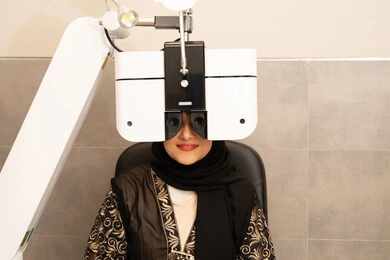 مفهوم الخدمات والرعاية الصحية في المشافي والمراكز الطبية، امراه عربيه خليجيه اماراتيه تقوم بفحص عينيها بجهاز المنظار العيني، تشخيص وتحديد المشاكل البصرية، استخدام الأجهزة الحديثة المتطورة، سيدة سعودية تتأكد من صحة البصر ، تقييم مدى الرؤية والكشف عن الامراض العينية