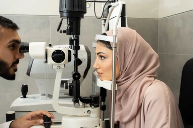 تشخيص وتحديد المشاكل البصرية، استخدام الأجهزة الحديثة المتطورة، طبيب عربي خليجي اماراتي يقوم بفحص عينى امراه اماراتية بجهاز المنظار العيني، تقييم مدى الرؤية والكشف عن الامراض العينية، مفهوم الخدمات والرعاية الصحية في المشافي والمراكز الطبية
