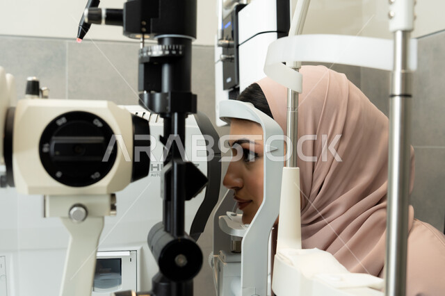 تشخيص وتحديد المشاكل البصرية، استخدام الأجهزة الحديثة المتطورة، امراه عربيه خليجيه اماراتيه تقوم بفحص عينيها بجهاز المنظار العيني، تقييم مدى الرؤية والكشف عن الامراض العينية، مفهوم الخدمات والرعاية الصحية في المشافي والمراكز الطبية ، سيدة سعودية تتأكد من صحة البصر