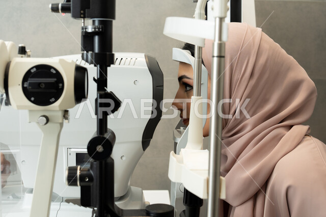 استخدام الأجهزة الحديثة المتطورة، تشخيص وتحديد المشاكل البصرية، امراه عربيه خليجيه اماراتيه تقوم بفحص عينيها بجهاز المنظار العيني، تقييم مدى الرؤية والكشف عن الامراض العينية، مفهوم الخدمات والرعاية الصحية في المشافي والمراكز الطبية ، سيدة سعودية تتأكد من صحة البصر