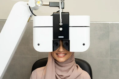 A Saudi woman uses advanced modern devices, the concept of services and healthcare in hospitals and centers, diagnosing and identifying visual problems, assessing vision and detecting eye diseases, an Arab Gulf Emirati woman wearing an abaya in front of an eye examination device to ensure the health of her eyesight.