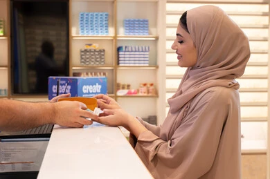 Acquiring gifts from one of the UAE malls, gestures of happiness and joy, the latest trendy eyewear products, following the latest fashion and beauty trends, a Saudi woman is shopping, an Emirati Gulf Arab woman wearing a colorful abaya is buying sunglasses.