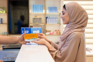 Gestures of happiness and joy, the latest products of modern trendy glasses, following the latest fashion and beauty trends, a Saudi woman shopping and buying, acquiring gifts from one of the Emirati malls, an Arab Gulf Emirati woman wearing a colored abaya is buying sunglasses.