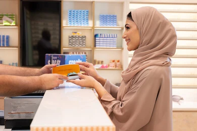 The latest products of modern trendy glasses, following the latest fashion and beauty trends, a Saudi woman shopping and buying gifts from one of the Emirati malls, an Arab Gulf Emirati woman wearing a colorful abaya buying sunglasses, gestures of happiness and joy.