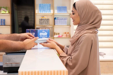 Following the latest trends in fashion and beauty, a Saudi woman is shopping and purchasing gifts from one of the Emirati malls. An Emirati Gulf Arab woman wearing a colorful abaya is buying sunglasses, showing gestures of happiness and joy, the latest products in modern trendy eyewear.