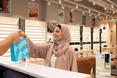 امراة سعودية تقوم بشراء نظارة شمسية،سيدة عربية خليجية اماراتية في متجر اماراتي, مفهوم التسوق و التبضع من المول ، اقتناء أحدث منتجات النظارات العصرية الحديثة,  متابعة آخر صيحات الموضة والجمال