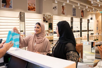 اقتناء أحدث منتجات النظارات العصرية الحديثة, صديقتان عربيان خليجيان اماراتيان في متجر اماراتي, امراة اماراتيه تقوم بشراء نظارة شمسية، مفهوم التسوق و التبضع من المول ، متابعة آخر صيحات الموضة والجمال