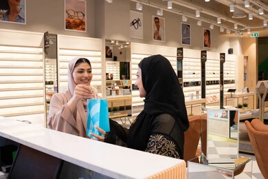 Following the latest trends in fashion and beauty, acquiring the latest products of modern stylish eyewear, two Arab Gulf Emirati friends in an Emirati store, an Emirati woman buying sunglasses, the concept of shopping and browsing from the mall.