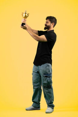 Favorite team winning, cheering for clubs and national teams, fun recreational activities, Saudi young man standing with gestures of joy and happiness, side portrait of an Arab Gulf Emirati man wearing casual clothes raising the golden cup, full body photo, yellow background