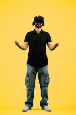 مشاهدة الأفلام ومحاكاة العالم الخيالي, بورتريه لشاب عربي سعودي خليجي يرتدي الزي الكاجوال ونظارة في آر ثلاثية الأبعاد, التفاعل والاندماج مع ألعاب الواقع الافتراضي,  رجل اماراتي يرفع قبضة يده لمحاولة إمساك شيء ما، صورة الجسم بالطول الكامل، خلفية صفراء