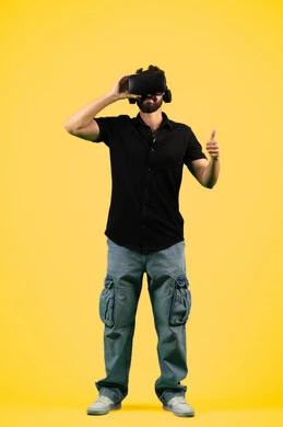 التفاعل والاندماج مع ألعاب الواقع الافتراضي, مشاهدة الأفلام ومحاكاة العالم الخيالي, بورتريه لشاب عربي سعودي خليجي يرتدي الزي الكاجوال ونظارة في آر ثلاثية الأبعاد, رجل اماراتي يرفع اصبع الابهام بتعابير الاعجاب بالتقنية، صورة الجسم بالطول الكامل، خلفية صفراء