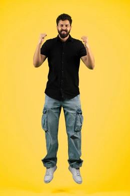 إتقان فنون الملاكمة، زيادة قدرة العضلات على التحمل، بورتريه لشاب عربي خليجي اماراتي مبتسم يرتدي الزي الكاجوال يرفع قبضات يديه بإيماءات القوة، رجل سعودي ينظر إلى الكاميرا بتعابير الثقة بالنفس، ممارسة رياضة الدفاع عن النفس، صورة الجسم بالطول الكامل، خلفية صفراء