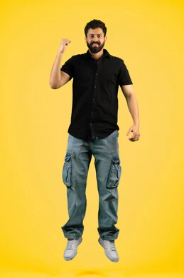 Victory and triumph of the favorite team, mastery of boxing arts, increased muscle endurance, portrait of a smiling young Arab Gulf Emirati man in casual clothes raising his fists with gestures of strength and victory, a Saudi man looking at the camera with an expression of self-confidence, full body, yellow background