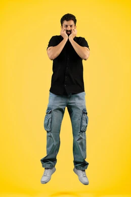 التفاجؤ من موقف محدد، الشعور بالدهشة والذهول, تذكر شيء ما، تلقي اخبار سعيدة غير متوقعة، شاب اماراتي ينظر إلى الكاميرا بايماءات الصدمة والتعجب والانبهار, بورتريه لرجل عربي سعودي خليجي يرتدي ملابس كاجوال صيفية ويضع يديه على وجهه، صورة لكامل الجسم، خلفية صفراء