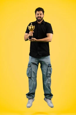 Cheering for clubs and national teams, fun recreational activities, a young Saudi man looking at the camera with gestures of joy and happiness for his favorite team's victory, a smiling Arab Gulf Emirati man wearing casual clothes holding the golden cup in his hand, full body photo, yellow background