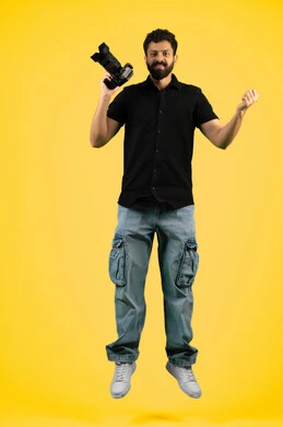 Mastering photography using high-resolution digital cameras, a professional Saudi photographer taking souvenir photos, raising his fist with gestures of joy and victory, a portrait of a young Arab Gulf Emirati man wearing casual clothes holding a camera, full body photo, yellow background