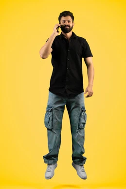 التواصل مع الأهل والأصدقاء, رجل إماراتي ينظر إلى الكاميرا بإيماءات البشاشة، متابعة آخر الأخبار والمستجدات حول العالم, دمج التقنيات الحديثة والتكنولوجيا بالحياة العملية, بورتريه لشاب عربي خليجي سعودي يرتدي الزي الكاجوال يجري مكالمة هاتفية، خلفية صفراء