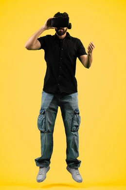 Watching movies and simulating a fantasy world, portrait of a young Saudi Arabian Gulf man wearing casual clothes and 3D VR glasses, interacting and immersing himself in virtual reality games, Emirati man raising his fist to try to grab something, full body image, yellow background