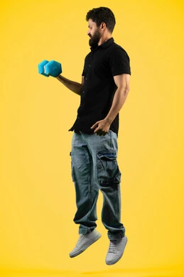 نشاط بدني للمحافظه على الصحه واللياقه الجسديه, شاب اماراتي يمارس رفع الأثقال (دمبلز), بناء جسم صحي, حرق الدهون والسعرات الحرارية, بورتريه من الجانب لرجل عربي خليجي سعودي يرتدي الزي الكاجوال يحمل الاوزان الحديديه، الجسم بالطول الكامل، خلفية صفراء