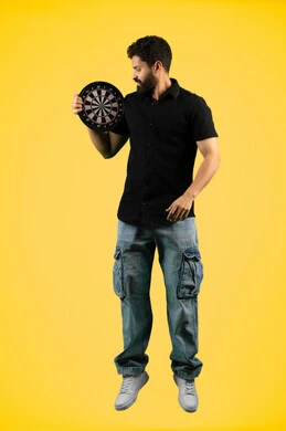 The concept of focus and goal setting, entertainment and sports skills, expressions of pleasure and happiness, portrait of a smiling Emirati Gulf Arab man in casual clothes holding a magnetic darts game, full body, yellow background