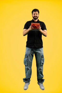 تقديم الهدايا بالاعياد والمناسبات الخاصة، مفهوم الشكر والامتنان، رجل سعودي ينظر إلى الكاميرا بايماءات الفرح والسرور، التعبير عن الحب والتقدير والاحترام، بورتريه لشاب عربي خليجي اماراتي يرتدي ازي الكاجوال يحمل بيديه صندوق هدية، الجسم بالطول الكامل، خلفية صفراء