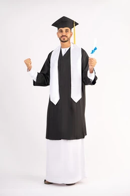 Raising a fist with an expression of achievement, pride in reaching dreams and success, looking at the camera with gestures of happiness and joy, celebrating the completion of university, portrait of an Arab Gulf Emirati graduate wearing a graduation cap and gown, holding a certificate in his hand, full body, white background