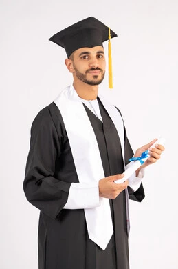 الاحتفال بإنهاء المرحلة الجامعية، تعابير السرور والسعادة بالنجاح، التقاط صور شخصية بثياب التخرج، بورتريه لشاب خريج عربي خليجي اماراتي مبتسم يرتدي القبعة وعباءة التخرج يحمل الشهادة ينظر الى الكاميرا بإيماءات البهجة، خلفية بيضاء