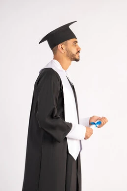 حمل الشهادة بتعابير الفروح والسرور، الشعور بالفخر والثقة بالنفس، الاحتفال بالنجاح وانهاء الدراسة الجامعية، مفهوم التفوق والاجتهاد، بورتريه لخريج عربي خليجي اماراتي يرتدي قبعة وثوب التخرج يقف باستقامة بايماءات السعادة، خلفية بيضاء