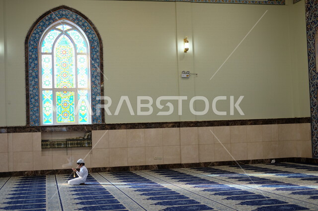 طفل عربي سعودي خليجي يجلس في المسجد, الصلاه والدعاء في المسجد, قراءة القران, التعبد في بيوت الله, ذكر الله