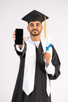 برامج وتطبيقات التعليم والدراسة اونلاين، بورتريه لشاب خريج عربي خليجي اماراتي مبتسم يرتدي القبعة وزي التخرج يمسك بيده الشهادة بتعابير السرور، الاحتفال بانتهاء المرحلة الجامعية، عرض شاشة سوداء فارغة على الهاتف المحمول، خلفية بيضاء