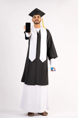 Online education and study applications, displaying a blank black screen on a mobile phone, a portrait of a smiling young Arab Gulf Emirati graduate wearing a cap and graduation gown, holding a certificate with an expression of joy, celebrating the end of the university stage, full body, white background