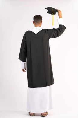 التعليم في الامارات العربية المتحدة، الشعور بالفخر والفرح بالوصول لحلم التخرج, بورتريه من الخلف لشاب خريج عربي خليجي اماراتي يرتدي عباءة يرفع قبعة التخرج، الاحتفال بإنهاء المرحلة الجامعية، الجسم بالطول الكامل، خلفية بيضاء