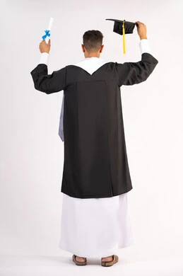Quality of education in the United Arab Emirates, feeling proud and happy to achieve the dream of graduation, portrait from the back of a young Arab Gulf Emirati graduate wearing an abaya raising the graduation cap and certificate, celebrating the completion of university, full body, white background