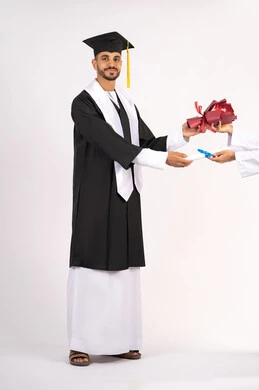 النظر الى الكاميرا بتعابير السرور والثقة بالنفس، استلام الشهادة بايماءات الفروح والسرور، الاحتفال بالنجاح وانهاء الدراسة الجامعية، مفهوم التفوق والاجتهاد، بورتريه لخريج عربي خليجي اماراتي يرتدي قبعة وثوب التخرج يقوم بأخذ باقة الورد، الجسم بالطول الكامل، خلفية بيضاء