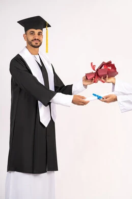 النظر الى الكاميرا بتعابير السرور والثقة بالنفس، استلام الشهادة بايماءات الفروح والسرور، الاحتفال بالنجاح وانهاء الدراسة الجامعية، مفهوم التفوق والاجتهاد، بورتريه لخريج عربي خليجي اماراتي يرتدي قبعة وثوب التخرج يقوم بأخذ باقة الورد، خلفية بيضاء