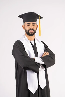 الجد والنجاح والاجتهاد، التقاط صور شخصية بثياب التخرج، الاحتفال بإنهاء المرحلة الجامعية، بورتريه لشاب خريج عربي خليجي اماراتي مبتسم يرتدي القبعة وعباءة التخرج يقف بأيدي متقاطعة ينظر الى الكاميرا بتعابير الثقة بالنفس، خلفية بيضاء