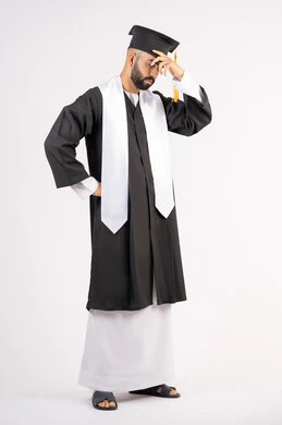 Exhaustion and fatigue after hard work and perseverance, finishing university studies after suffering, portrait of a young Arab Gulf Emirati graduate wearing a cap and graduation gown, putting his hand on his head with an expression of despair, waiting impatiently for results, full body, white background