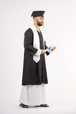 حمل الشهادة بتعابير الفروح والسرور، الشعور بالفخر والثقة بالنفس، الاحتفال بالنجاح وانهاء الدراسة الجامعية، مفهوم التفوق والاجتهاد، بورتريه لخريج عربي خليجي اماراتي يرتدي قبعة وثوب التخرج يقف باستقامة بايماءات السعادة، الجسم بالطول الكامل، خلفية بيضاء