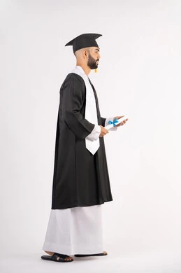 الوصول لحلم النجاح، تعابير السعادة والسرور، مناسبة واحتفال جامعي، الاحتفال بإنهاء الدراسة الجامعية، مفهوم الاجتهاد والتفوق، بورتريه لشاب خريج عربي خليجي اماراتي مبتسم يرتدي عباءة التخرج يمسك بيده الشهادة، الجسم بالطول الكامل، خلفية بيضاء