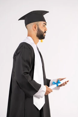الشعور بالفخر والثقة بالنفس، الاحتفال بالنجاح وانهاء الدراسة الجامعية، مفهوم التفوق والاجتهاد، بورتريه لخريج عربي خليجي اماراتي يرتدي قبعة وثوب التخرج يقف باستقامة بايماءات السعادة،  حمل الشهادة بتعابير الفروح والسرور، خلفية بيضاء