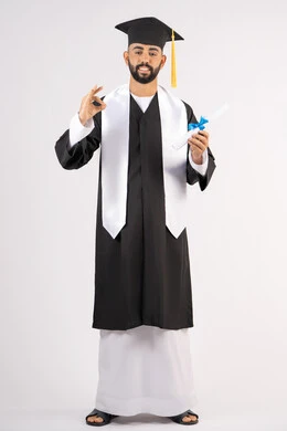 A mark of quality, excellence and distinction, celebrating the achievement of dreams, celebrating the completion of university, a portrait of a young Arab Gulf Emirati graduate wearing a graduation cap and gown, holding a certificate in his hand, looking at the camera with happy gestures, full body, white background