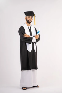 مفهوم التفوق والنجاح والاجتهاد، التقاط صور شخصية بثياب التخرج، الاحتفال بإنهاء المرحلة الجامعية، بورتريه لشاب خريج عربي خليجي اماراتي مبتسم يرتدي القبعة وعباءة التخرج يقف بأيدي متقاطعة ينظر الى الكاميرا بتعابير الثقة بالنفس، الجسم بالطول الكامل، خلفية بيضاء
